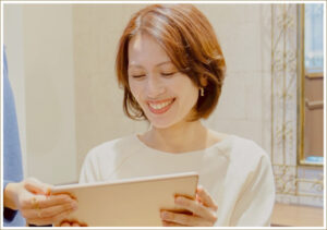 タブレットでカタログを見ながら美容師と相談している女性