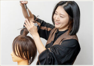 マネキンにウィッグをつけて調整をする美容師
